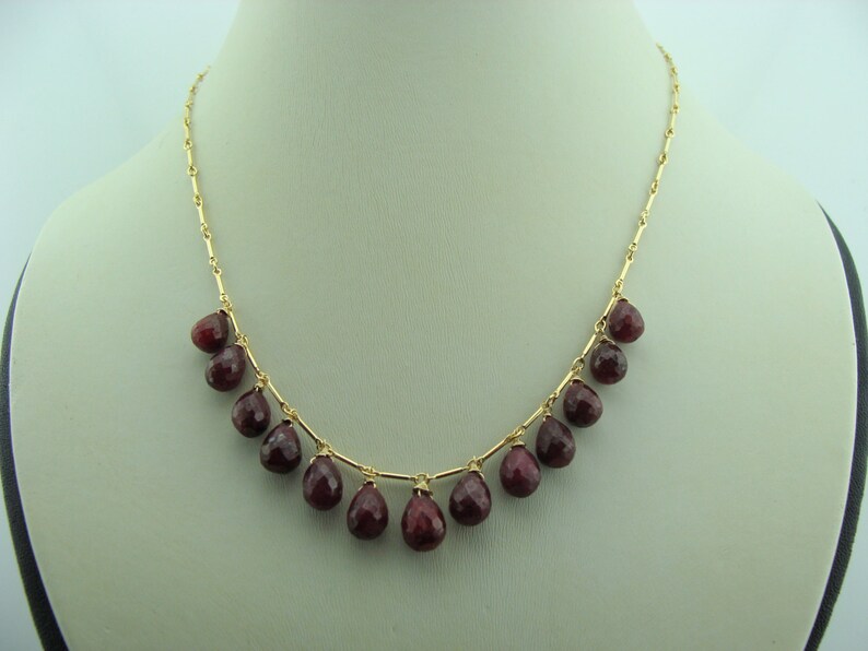 May include: A gold chain necklace with teardrop-shaped red gemstones.