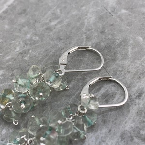 May include: A pair of silver dangle earrings featuring light blue gemstone beads. The earrings have a teardrop-shaped gemstone at the bottom.