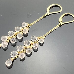 Pu&ograve; includere: Orecchini pendenti in oro con un design a cascata di pietre di quarzo chiare.