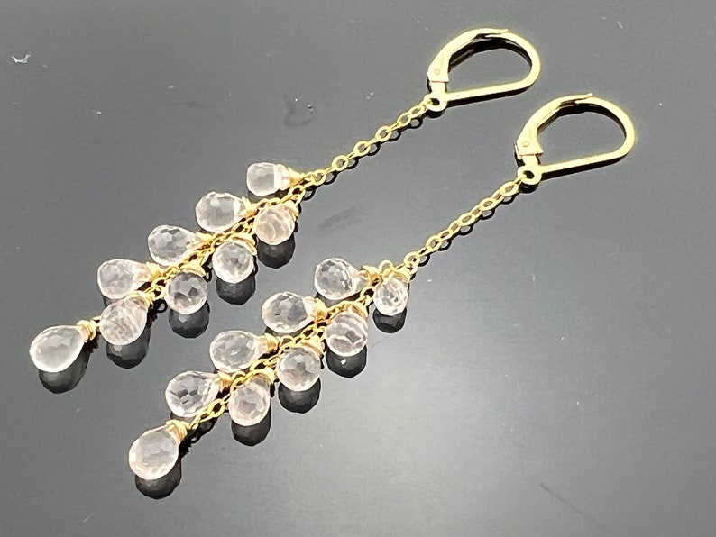 Pu&ograve; includere: Orecchini pendenti in oro con un design a cascata di pietre di quarzo chiare.