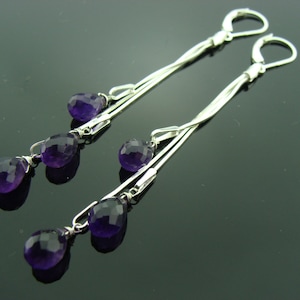 May include: A pair of silver dangle earrings with multiple strands and purple amethyst gemstone drops.