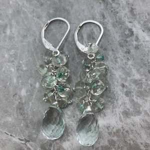 May include: A pair of silver dangle earrings featuring a cluster of light blue and green gemstone beads, with a larger teardrop-shaped gemstone at the bottom.