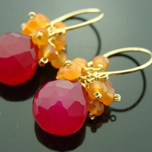 May include: Gold earrings with a teardrop-shaped pink chalcedony gemstone and orange carnelian beads.