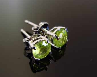 Könnte beinhalten: Ein Paar silberne Ohrringe mit grünen Peridot-Edelsteinen. Die Ohrringe haben ein schlichtes Design und sind perfekt für den Alltag.