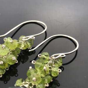 Op de afbeelding: Een paar zilveren oorhangers met groene edelsteen kralen. De oorbellen hebben een eenvoudige haak sluiting.