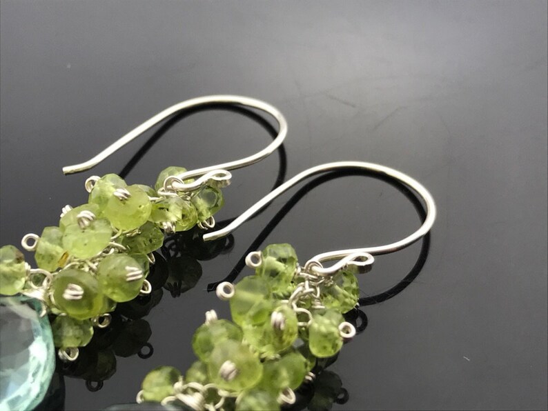 Op de afbeelding: Een paar zilveren oorhangers met groene edelsteen kralen. De oorbellen hebben een eenvoudige haak sluiting.
