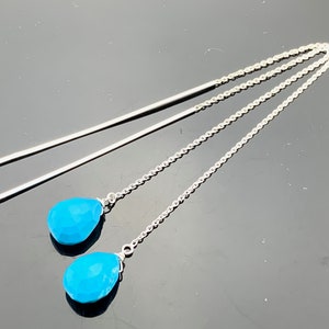 May include: A pair of silver dangle earrings with turquoise teardrop-shaped stones.