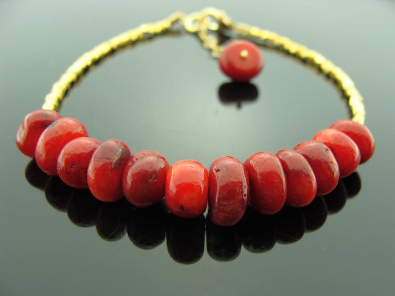 Op de afbeelding: Een rode koraal kralen armband met een gouden ketting en een kleine rode koraal bedel.
