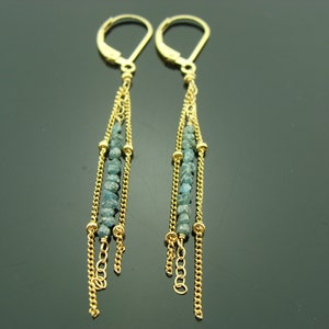 Puede incluir: Pendientes de oro con un dise&ntilde;o largo y colgante. Los pendientes presentan m&uacute;ltiples hebras de cadena con peque&ntilde;as cuentas de piedras preciosas azules.