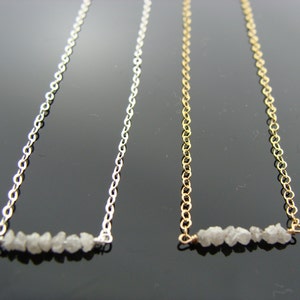 May include: Two delicate necklaces with a bar of rough diamonds. One necklace is silver and the other is gold.