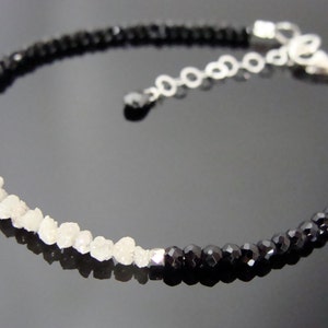 May include: A silver chain bracelet with black and white beads. The bracelet has a silver clasp and is made with rough cut stones.