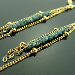 Puede incluir: Un par de pendientes de cadena de oro con diamantes en bruto azules. Los pendientes tienen un dise&ntilde;o de cadena delicado y est&aacute;n acentuados con peque&ntilde;os diamantes azules irregulares.