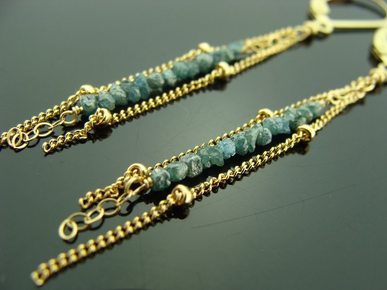 Puede incluir: Un par de pendientes de cadena de oro con diamantes en bruto azules. Los pendientes tienen un dise&ntilde;o de cadena delicado y est&aacute;n acentuados con peque&ntilde;os diamantes azules irregulares.