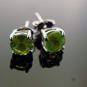 May include: A pair of silver earrings with green gemstone studs.