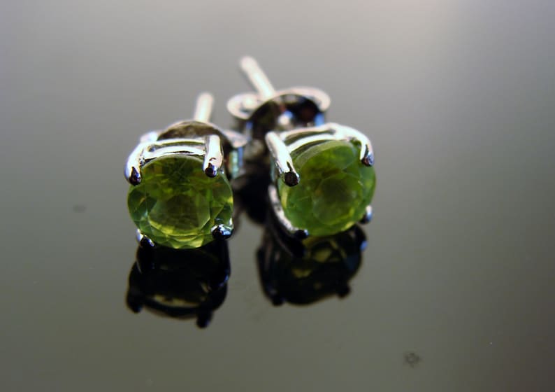 May include: A pair of silver earrings with green gemstone studs.