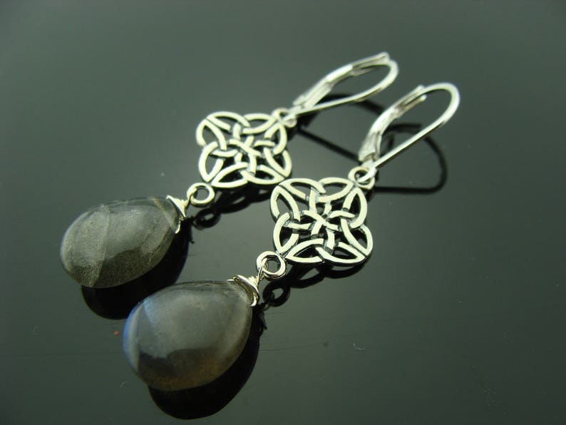 May include: Silver earrings with a Celtic knot design and gray gemstone drops.