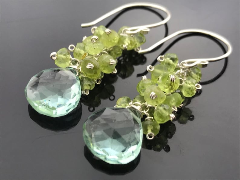 Op de afbeelding: Een paar zilveren oorhangers met lichtgroene edelsteen kralen en een grotere lichtgroene edelsteen druppel.