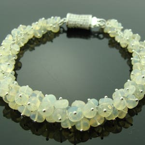 May include: A silver bracelet with a clasp and a row of white opal beads.