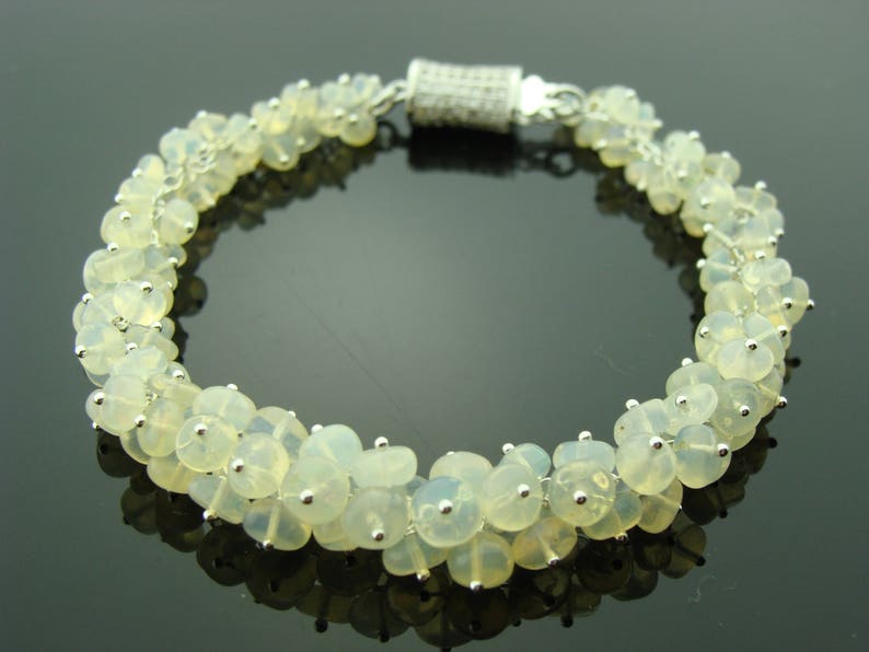 May include: A silver bracelet with a clasp and a row of white opal beads.