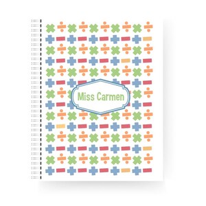 May include: A spiral-bound notebook with a white cover featuring a colourful pattern of mathematical symbols. The symbols are in orange, green, blue, and red. The notebook has the text "Miss Carmen" in a blue and white frame.