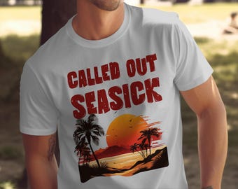 May include: White t-shirt featuring the text "CALLED OUT SEASICK" in red, above a sunset scene with palm trees and a beach. The graphic design includes a vibrant orange sun and palm tree silhouettes.
