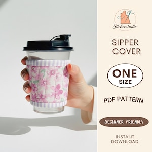 May include: A clear travel mug with a black lid and a floral patterned cozy. The cozy is quilted with pink flowers and a lavender striped top and bottom. The text on the side says "Sipper Cover" and "One Size".