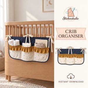 May include: A navy blue quilted crib organizer with three pockets featuring mustard yellow ruffled trim and a cream-colored fabric with a moon and star pattern. The organizer is secured to a wooden crib with cream-colored fabric ties.