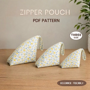 May include: Three triangular zipper pouches in varying sizes, featuring a white fabric with a yellow and blue floral pattern. The text ZIPPER POUCH PDF PATTERN, THREE SIZE, and BEGINNER FRIENDLY are visible on the image.