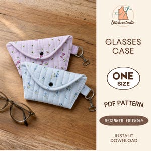 Puede incluir: Dos estuches para gafas de tela acolchada con estampados florales en azul claro y morado claro, cada uno con cierre de botón a presión y anilla metálica. El texto incluye Sticheestudio, GLASSES CASE, ONE SIZE, PDF PATTERN, BEGINNER FRIENDLY, INSTANT DOWNLOAD.