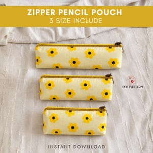 Peut inclure: Trois trousses à crayons rectangulaires de tailles différentes, fabriquées en tissu jaune clair avec un motif répétitif de fleurs jaunes à cœurs noirs. Chaque trousse présente une fermeture éclair jaune moutarde sur le dessus.