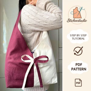 Puede incluir: Un bolso tote de dos tonos con una combinación de colores burdeos y crema. El bolso está dividido verticalmente, con un panel burdeos a la izquierda y un panel crema a la derecha. Un lazo crema adorna la parte delantera. El bolso es parte de un patrón PDF.