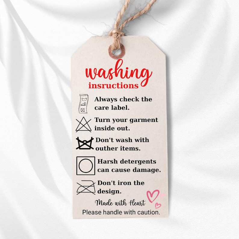 a white tag with instructions for washing clothes, including checking the care label, turning the garment inside out, avoiding harsh detergents, and not ironing the design.