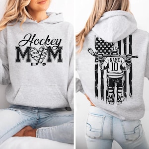 A woman wearing a grey hoodie with a graphic design on the front and a graphic on the back.