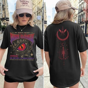 A woman wearing a black t-shirt with a dragon design and text on it, standing on a city street.