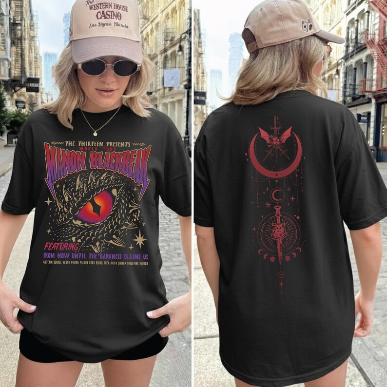 A woman wearing a black t-shirt with a dragon design and text on it, standing on a city street.