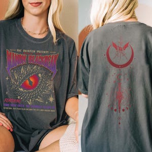 a woman wearing a black t-shirt with a dragon design and text on it.