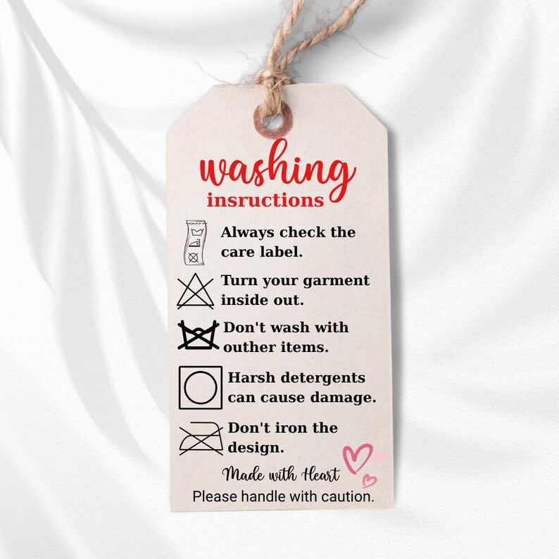 a white tag with instructions for washing clothes, including checking the care label, turning the garment inside out, avoiding harsh detergents, and not ironing the design.
