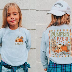 May include: A light blue crewneck sweatshirt featuring a small pumpkin graphic and the name Sarah on the front left chest. The back displays a large graphic with pumpkins, autumn leaves, and the text Pumpkin Patch Crew and Fun Fall Memories.