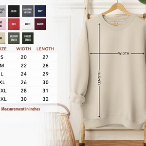 a beige sweater hanging on a wooden hanger, with a size chart and measurements provided below it.