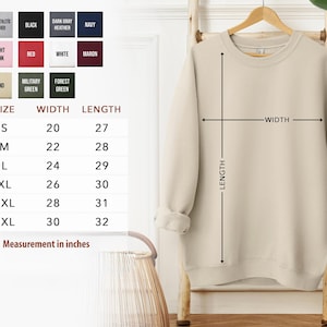 a beige sweater hanging on a wooden hanger, with a size chart and measurements provided below it.