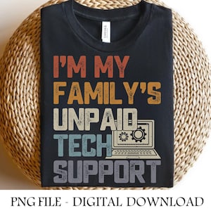 Puede incluir: Camiseta negra con el texto "I'M MY FAMILY'S UNPAID TECH SUPPORT" en naranja, amarillo, turquesa y gris. Incluye un gráfico de un portátil con engranajes. La camiseta se muestra sobre una superficie circular tejida.