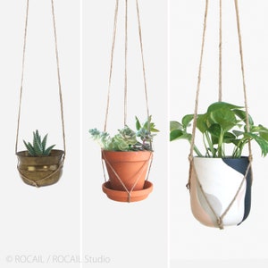 May include: Three hanging planters with different styles and plants. The first planter is a brass pot with a succulent plant. The second planter is a terracotta pot with a succulent plant. The third planter is a white ceramic pot with a green plant and abstract patterns.