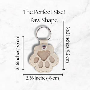 May include: A beige paw-shaped keychain with a silver keyring. The keychain measures 2.16 inches (5.5 cm) wide, 2.36 inches (6 cm) long, and 3.62 inches (9.2 cm) high. The text "The Perfect Size! Paw Shape" is above the keychain.