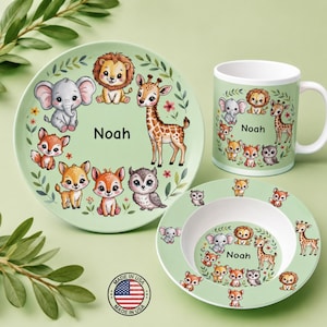 May include: A light green dinnerware set including a plate, a bowl, and a mug, each featuring illustrations of a lion, elephant, giraffe, fox, and owl with the name Noah printed in black text. A circular Made in USA logo is visible.