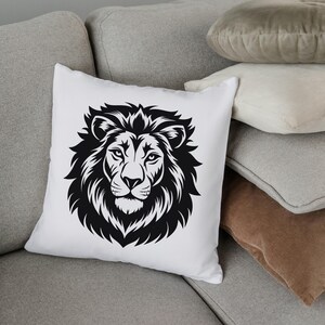 May include: White square throw pillow featuring a detailed black illustration of a lion's head. The lion's mane is prominently displayed, with intricate lines and shading. The pillow is placed on a gray sofa with other pillows in the background.