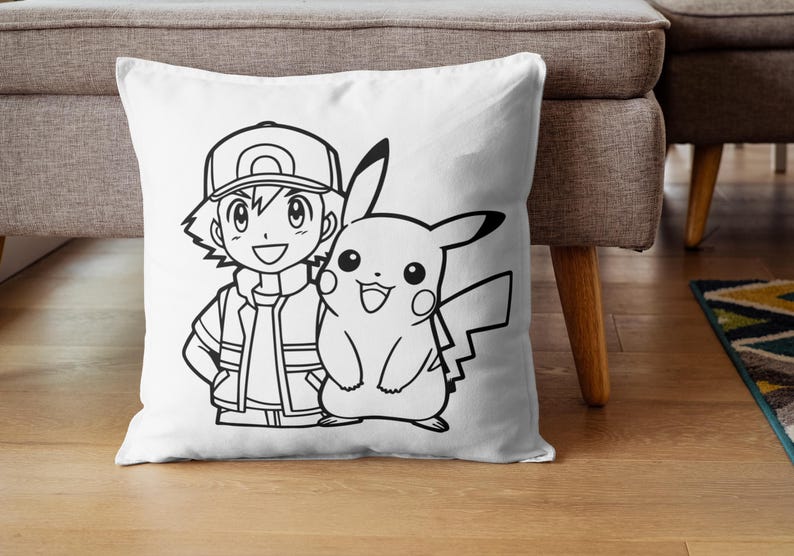 May include: White square pillow featuring a black and white illustration of a cartoon character with a cap and a smiling Pikachu. The pillow is placed on a wooden floor.