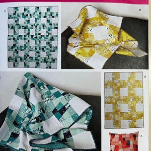 May include: A Simplicity sewing pattern featuring quilt and pillow designs. The quilts showcase patchwork patterns in shades of green, yellow, and red. The pattern includes the text "U.S. ONE SIZE" and "Simplicity".