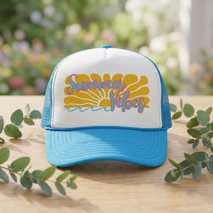 May include: A blue and white trucker hat with a curved peak. The front panel features the text "Summer Vibes" in yellow and purple, with a sun and wave design. The hat has a mesh back.