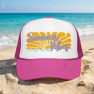 May include: A bright pink trucker hat with a white front panel featuring a yellow sun graphic and the text Summer Vibes in blue script. The hat has a structured front, a curved brim, and a mesh back panel for ventilation and a classic fit.