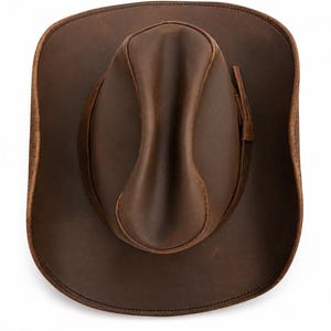 May include: A top-down view of a dark brown leather cowboy hat featuring a pinched crown and a wide, curved brim. The hat includes a matching leather hat band wrapped around the base of the crown, with visible stitching along the brim edge.